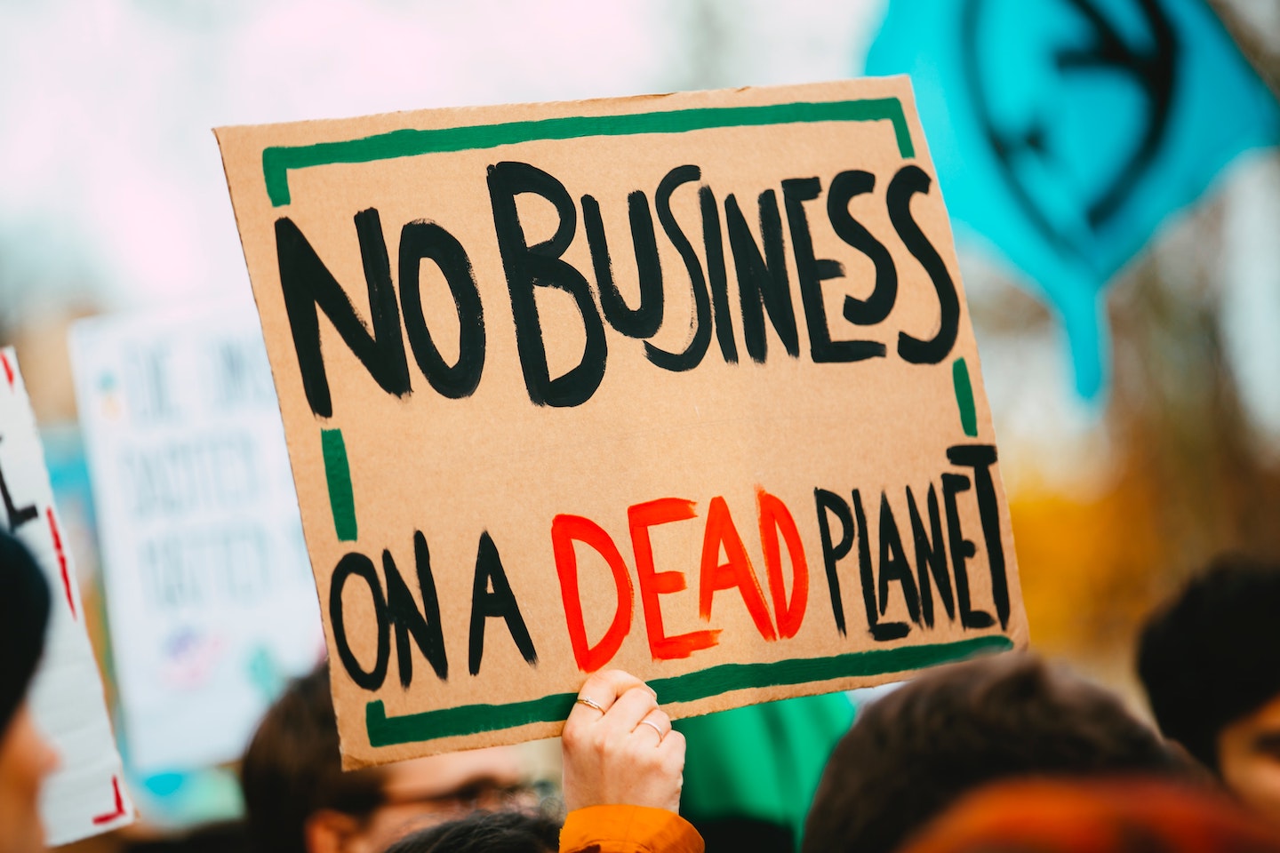 The image is of a person holding a sign that reads "No Business On A Dead Planet"